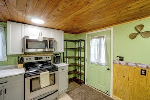 A kitchen with wooden ceiling, a stove, a microwave, and a coffee maker. - Walk to Lake Ontario! 'minnow Cottage' (Kent)