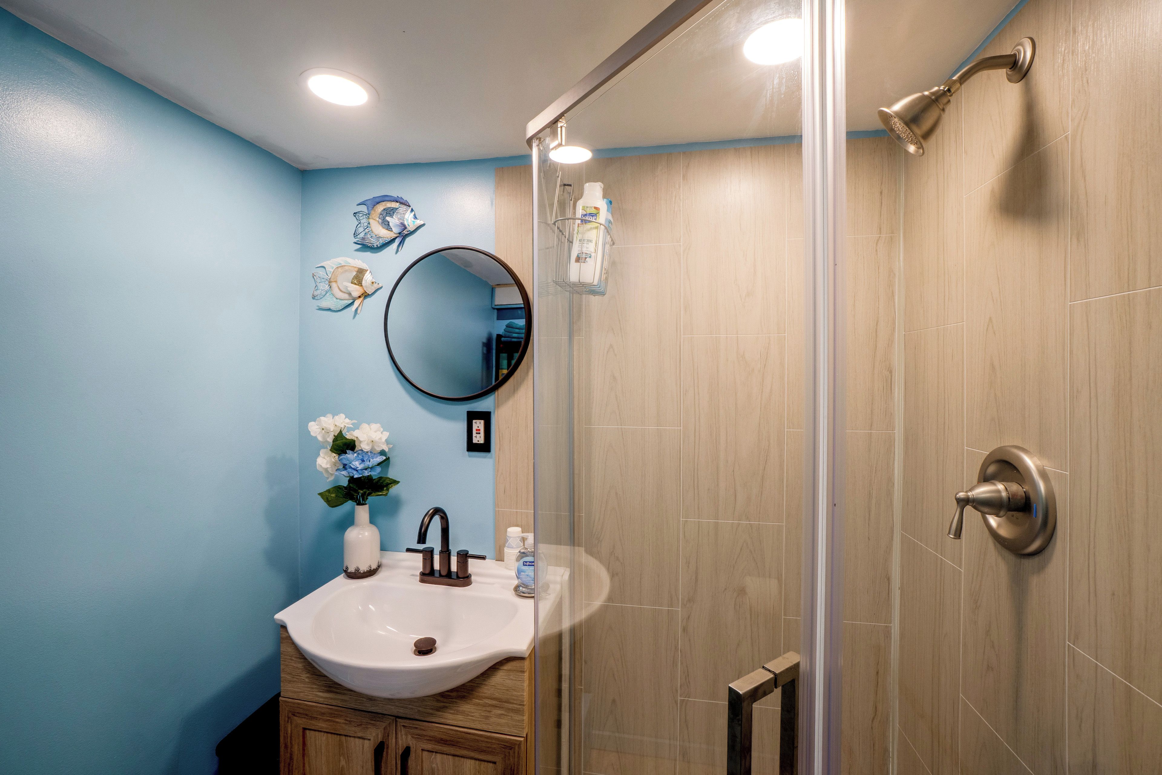 A bathroom with a sink, mirror, and shower.