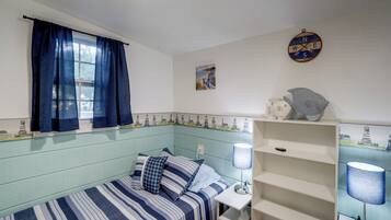 A room with a single bed, a desk, and a shelf with decorative items.