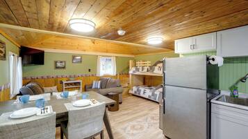 A compact kitchen with a refrigerator, a dining table with chairs, and a sofa.