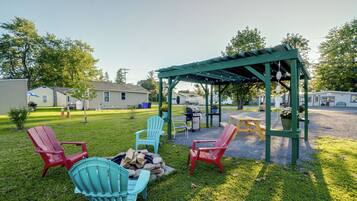 A backyard with a wooden pergola, outdoor seating, and a fire pit.