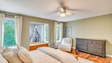 A bedroom with a bed, a dresser, a window with curtains, and a ceiling fan.