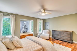 Un dormitorio con cama, cómoda, ventana con cortinas y ventilador de techo.