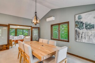 Un comedor con una mesa de madera, sillas y una araña.