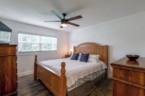 A bedroom with a wooden bed, a ceiling fan, a window with blinds, and a nightstand with a lamp. - Winter Haven Chain of Lakes Getaway Near Legoland (Winter Haven)