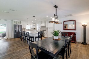 A modern kitchen with white cabinets, a central island, and pendant lighting. - Winter Haven Chain of Lakes Getaway Near Legoland (Winter Haven)