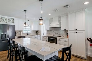 A modern kitchen with white cabinetry, a marble island, and pendant lighting. - Winter Haven Chain of Lakes Getaway Near Legoland (Winter Haven)