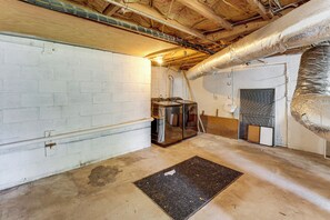 A basement with exposed ductwork, a water heater, and a door with a vent. - Commute to Atl! Home Near Canton St Eats (Roswell)