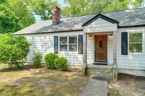 A single-story house with a front porch, a chimney, and a door with a decorative panel. - Commute to Atl! Home Near Canton St Eats (Roswell)