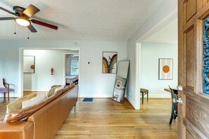 A spacious living area with a ceiling fan, a brown leather sofa, and a wooden floor. - Commute to Atl! Home Near Canton St Eats (Roswell)