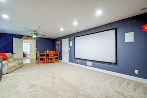 A home theater room with a large screen, ceiling fan, and seating area.