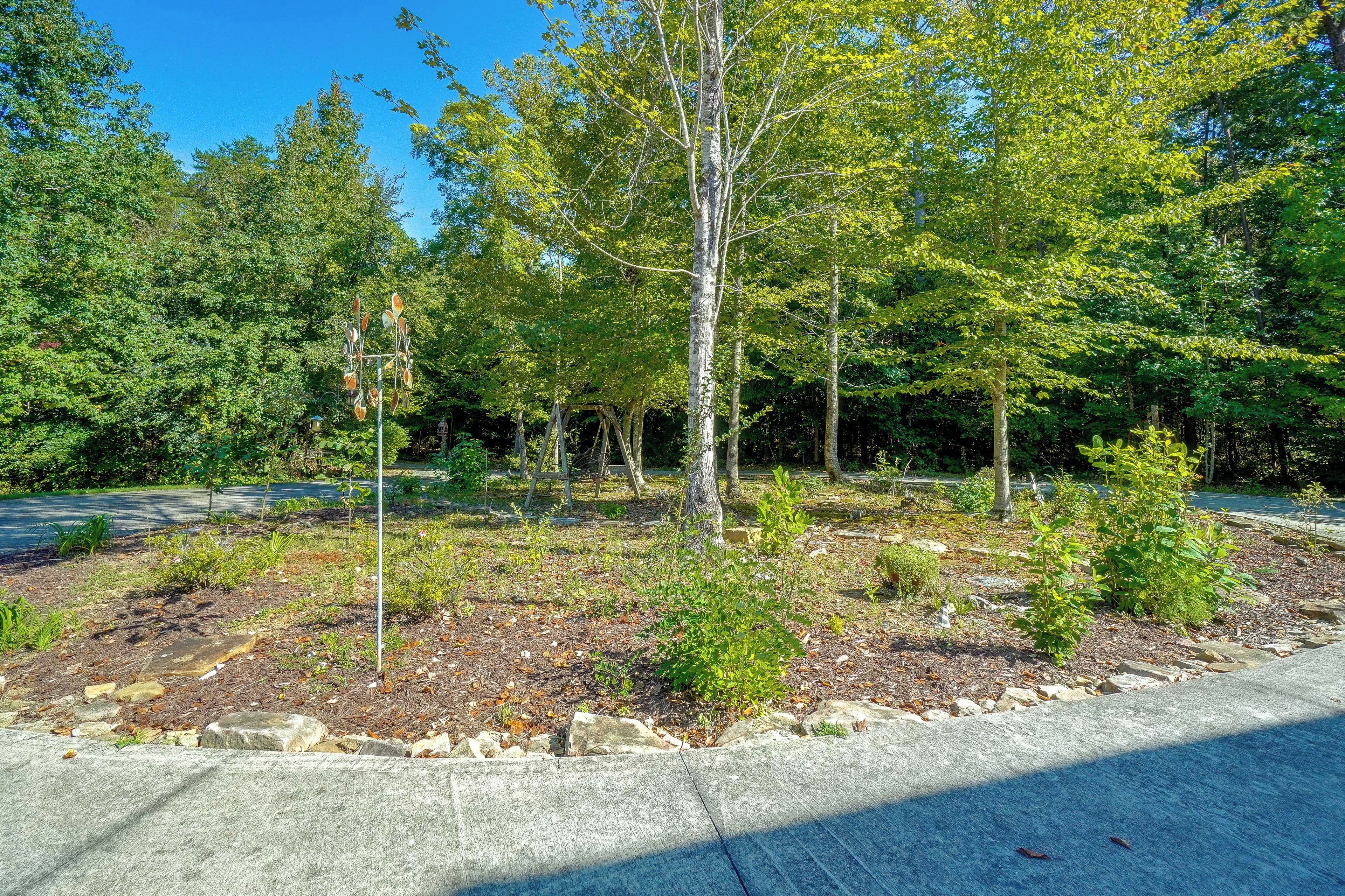 A landscaped area with trees, a paved path, and a stone border.