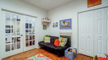 A room with a black sofa, a colorful rug, a white door, and a framed family photo on the wall.