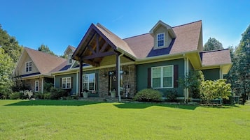 A two-story house with a stone facade, a gabled roof, and a covered front porch.