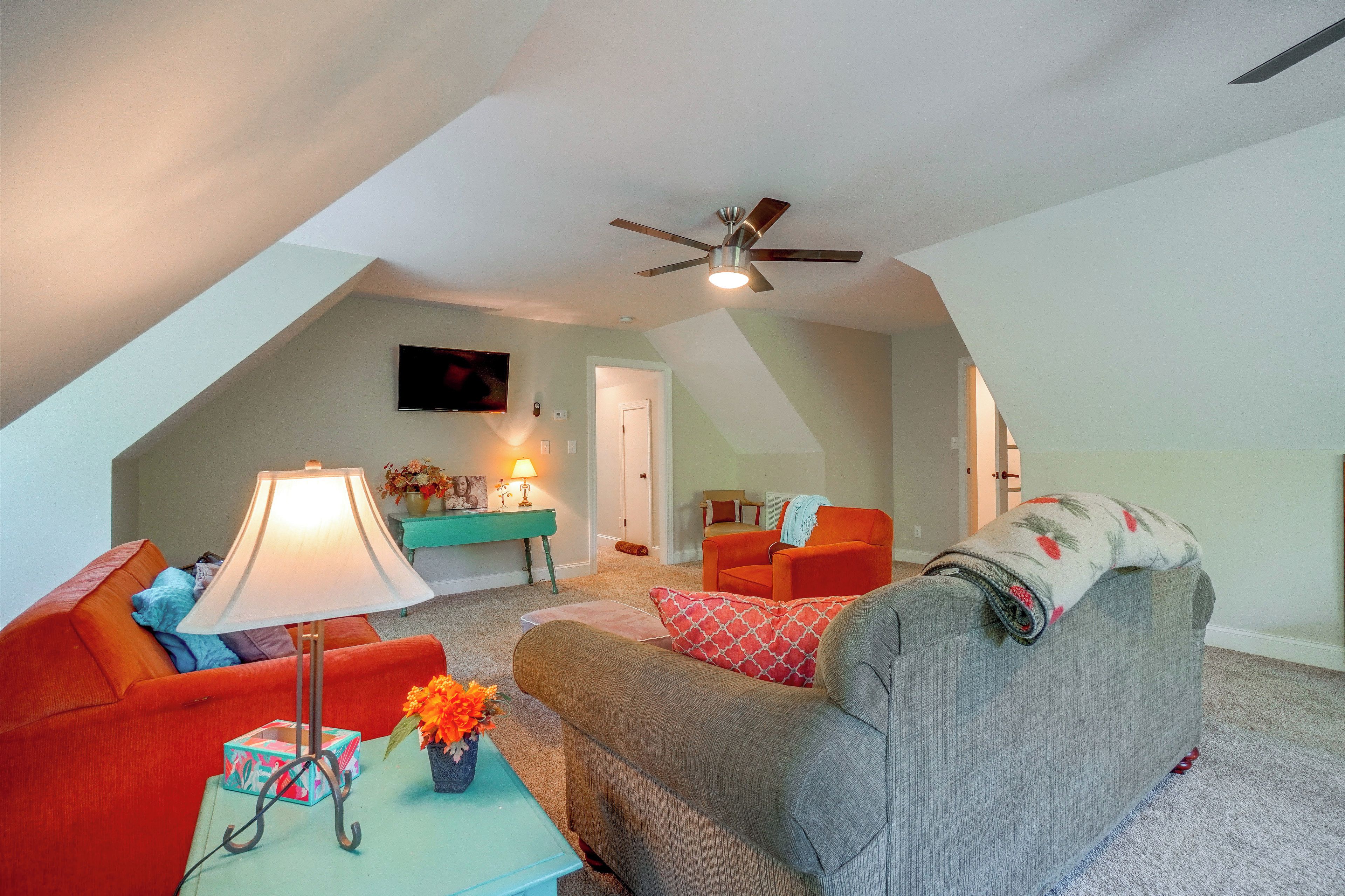 A cozy living room with a ceiling fan, a television, and a sofa.
