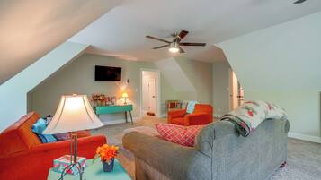 A cozy living room with a ceiling fan, a television, and a sofa.