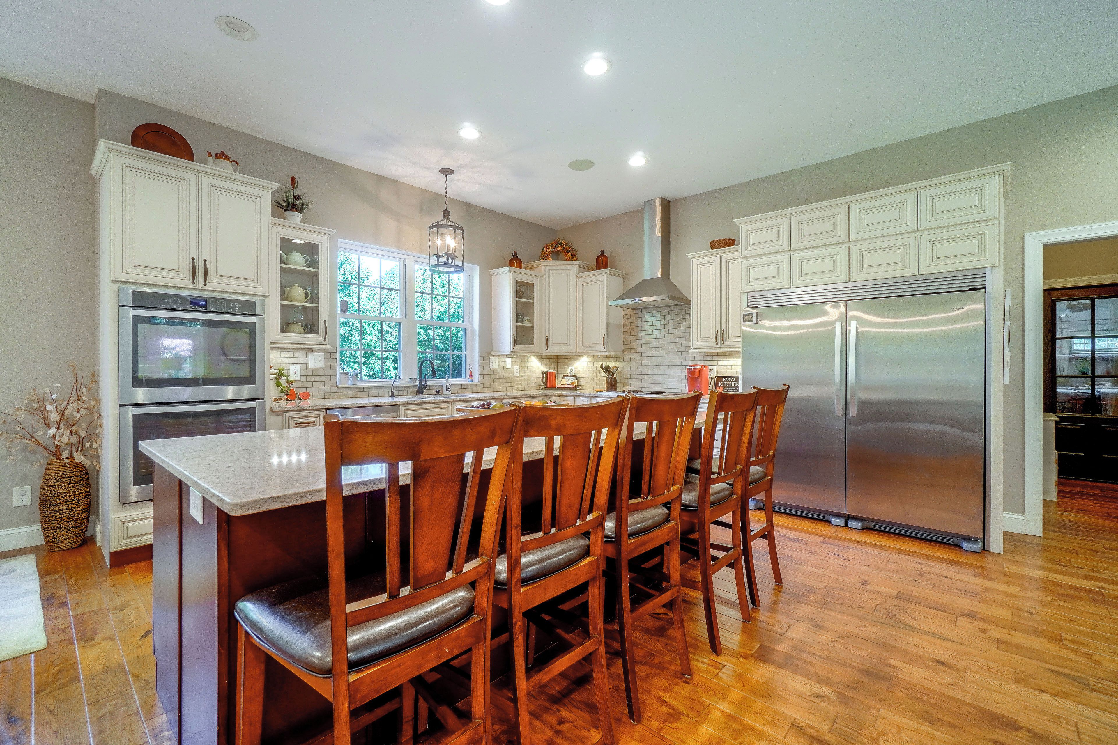 Una cocina con armarios blancos, electrodomésticos de acero inoxidable y una zona de comedor de madera.