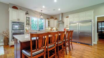Una cocina con armarios blancos, electrodomésticos de acero inoxidable y una zona de comedor de madera.