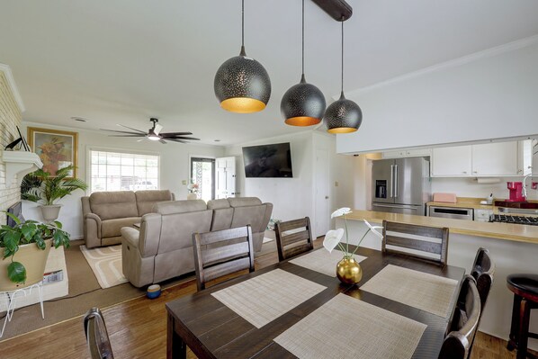 Una sala de estar moderna con sofá, mesa de comedor y zona de cocina con electrodomésticos.