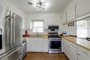 Una cocina moderna con electrodomésticos de acero inoxidable, una isla central y un ventanal con persianas.