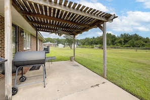 A covered patio area with a grill and a concrete floor.