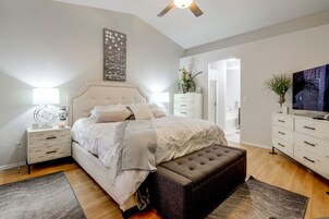 A bedroom with a bed, bedside tables, a TV, a dresser, and a ceiling fan.