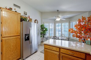 A kitchen with wooden cabinets, a stainless steel refrigerator, a water dispenser, and a ceiling fan. - Near Golf & Outdoor Fun! West Valley Retreat (Peoria)