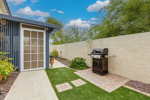 Un patio trasero con una parrilla, una planta en maceta y un pequeño jardín.