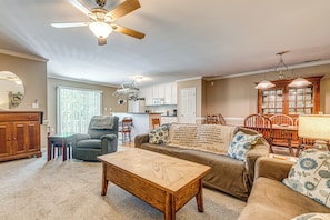 A spacious living room with a ceiling fan, a dining area with wooden chairs, and a kitchen in the background. - Raleigh-area Farm Stay w/ Pond: Swim, Fish, Relax! (Clayton)