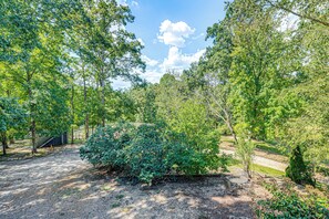 A covered outdoor seating area with a gravel ground, surrounded by trees and a clear sky. - Raleigh-area Farm Stay w/ Pond: Swim, Fish, Relax! (Clayton)