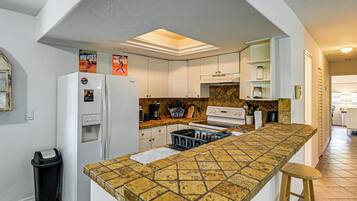 Una cocina con una isla central, armarios blancos, un refrigerador y un microondas.