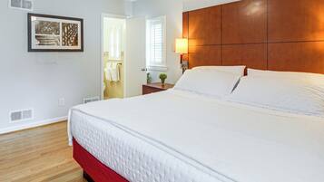 A hotel room with a large bed, a wooden headboard, a bedside table with a lamp, and a framed picture on the wall.