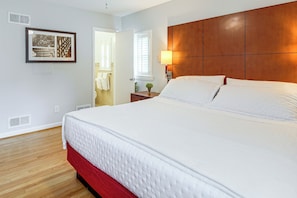 A hotel room with a large bed, a wooden headboard, a bedside table with a lamp, and a framed picture on the wall.