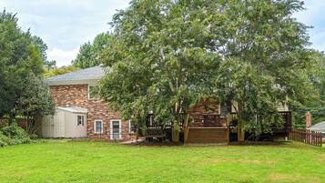 A brick house with a garage, a wooden deck, and a well-maintained lawn.