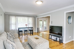 A living room with a sofa, a TV, a coffee table, and a dining area with a table and chairs.
