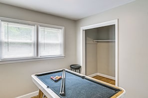 Quarto com mesa de bilhar, janela com persianas e porta para um armário.