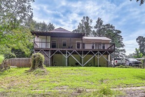 A two-story house with a balcony, surrounded by a fenced yard and trees.