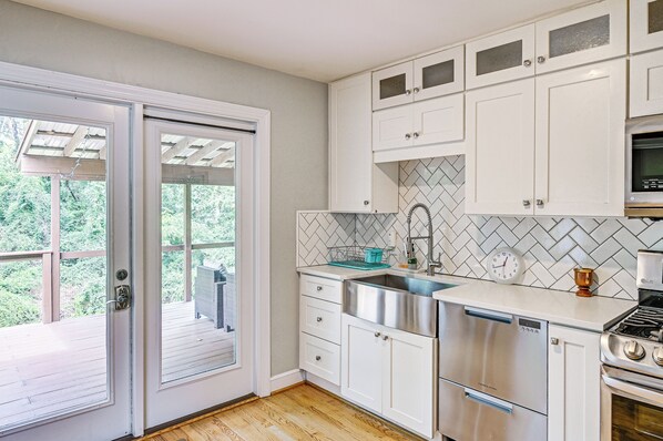 A modern kitchen with white cabinetry, a stainless steel sink, and a built-in oven.