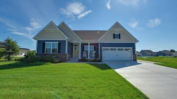 A two-story house with a garage, a front porch, and a well-maintained lawn.