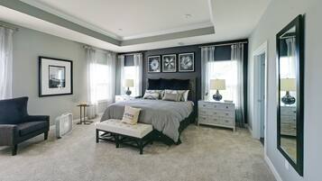 A bedroom with a large bed, bedside tables, a chair, and a bench.