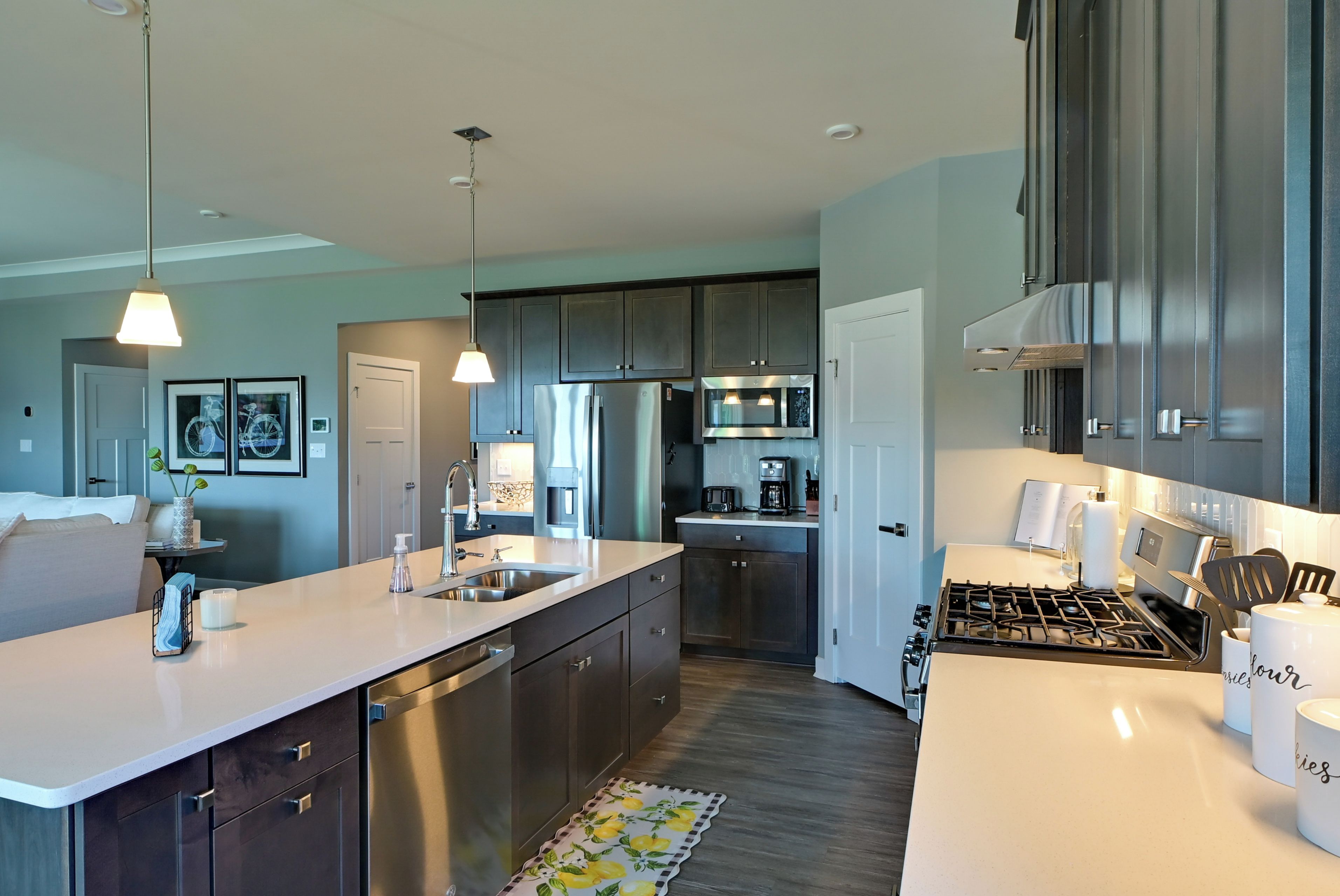 A modern kitchen with a central island, stainless steel appliances, and dark cabinetry.