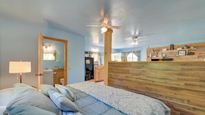 A bedroom with a bed, a wooden headboard, a ceiling fan, and a bathroom visible through an open door. - Hike, Fish & Unwind! Catskills Studio w/ Mtn Views (Hobart)