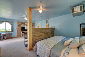 A bedroom with a bed, a desk, and a chair. There is a window with curtains, a ceiling fan, and a wall-mounted air conditioner. - Hike, Fish & Unwind! Catskills Studio w/ Mtn Views (Hobart)