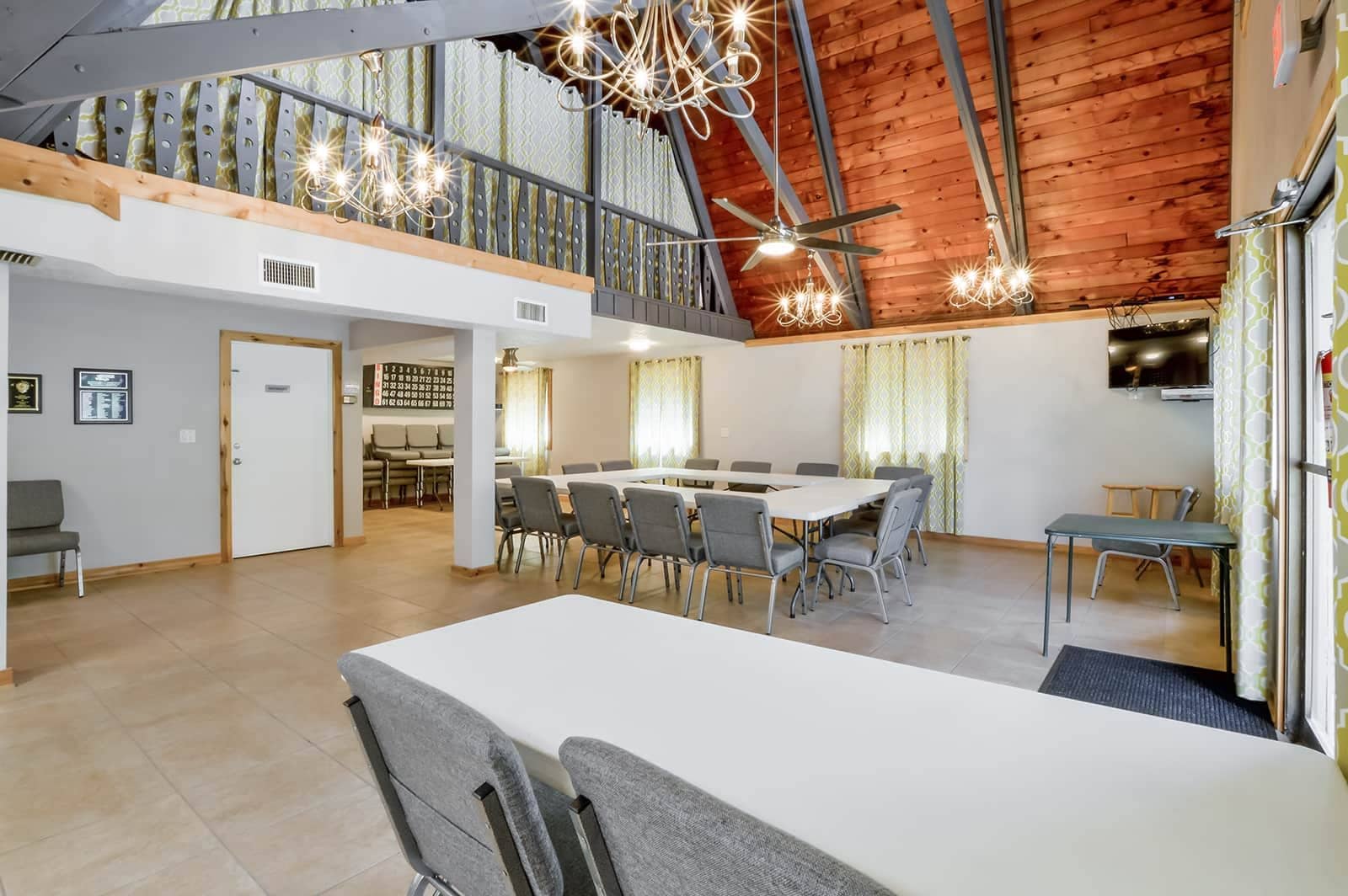 A spacious dining area with a high ceiling, modern lighting fixtures, and a view of the upper floor.