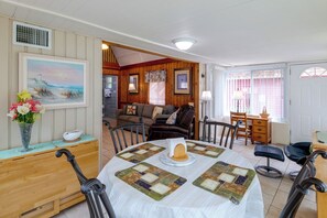 Ein gemütliches Wohnzimmer mit Esstisch, Stühlen, einer Couch und einem Bild an der Wand.