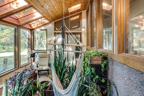 Quarto com rede, plantas em vasos e vista para o exterior.