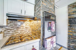A kitchen with a stainless steel refrigerator, a gas stove, and a tiled backsplash.