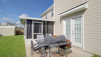 Une terrasse avec un barbecue, une porte vitrée et un mur en briques.
