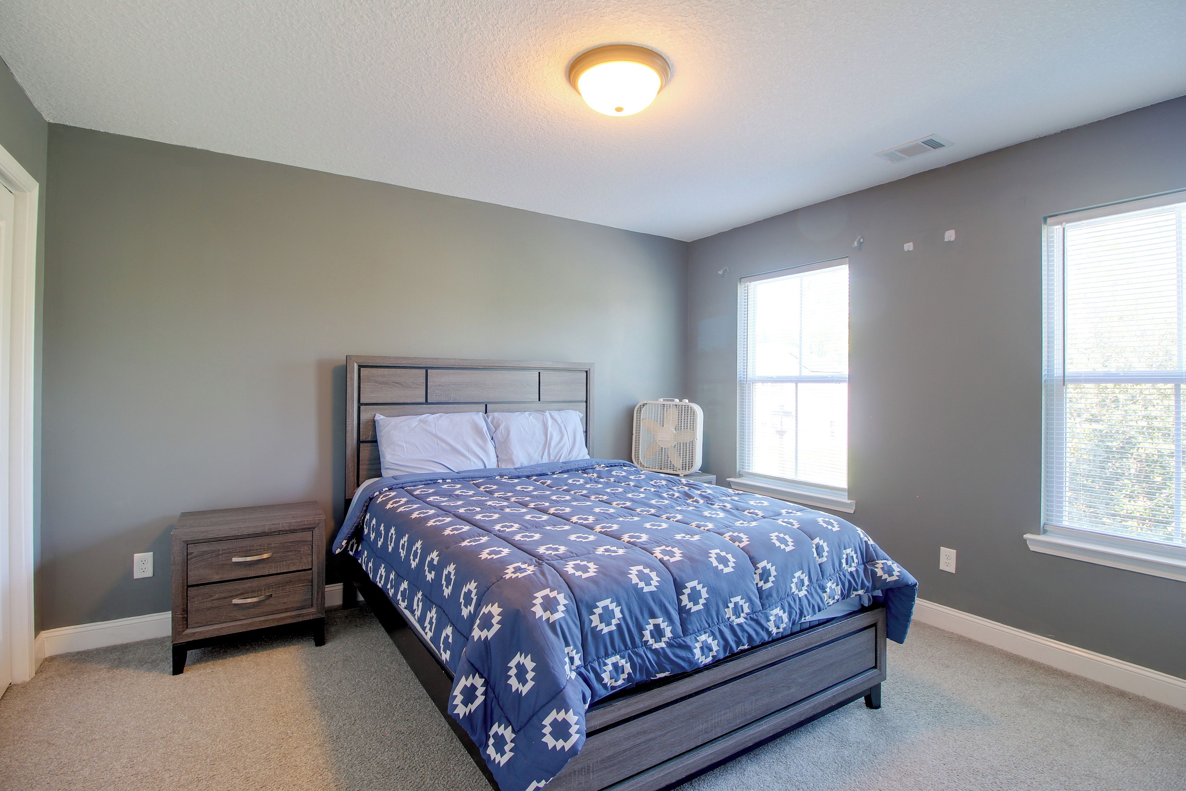A bedroom with a bed, nightstand, and window.