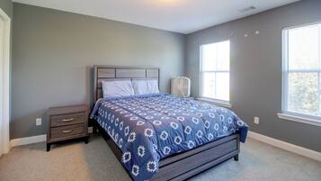 A bedroom with a bed, nightstand, and window.